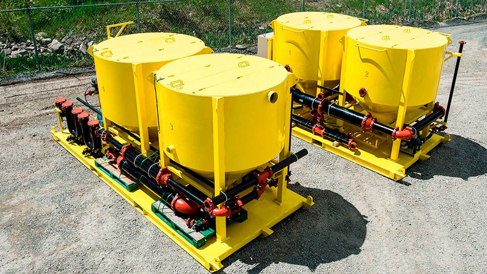 Camión rojo de plataforma larga transportando un gran decantador amarillo de la marca 'SYVERTECH' para el tratamiento de aguas residuales complejas, estacionado en una calle urbana con edificios y cielo despejado al fondo. - ver detalles