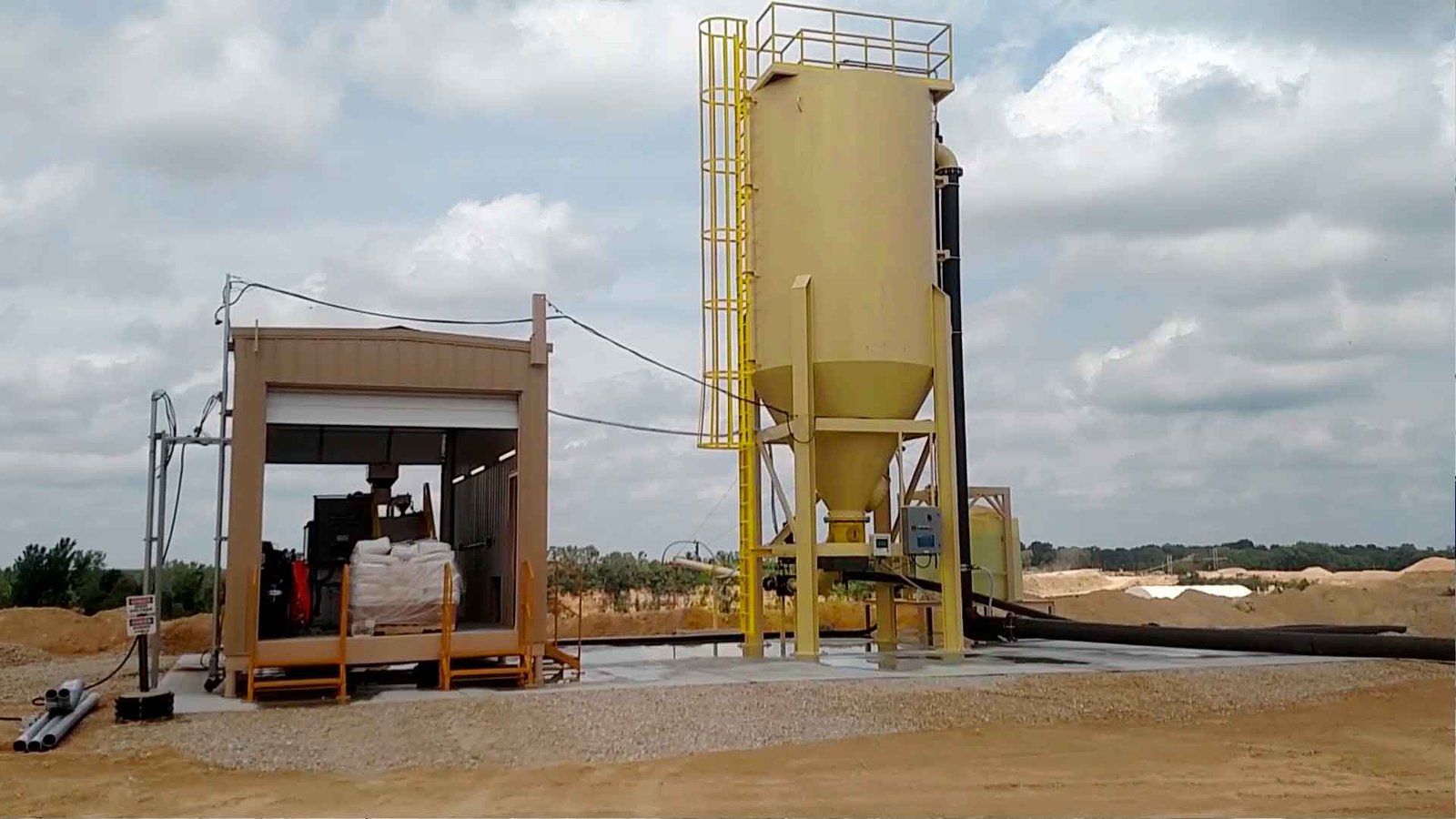 Camión rojo de plataforma larga transportando un gran decantador amarillo de la marca 'SYVERTECH' para el tratamiento de aguas residuales complejas, estacionado en una calle urbana con edificios y cielo despejado al fondo. - ver detalles